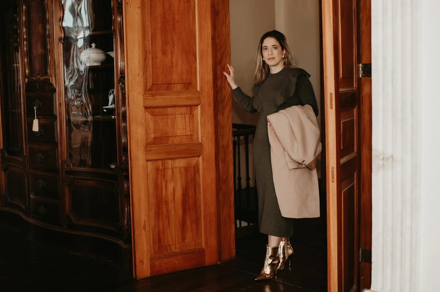 Cilene com look em tons neutros, em ambiente com portas de madeira